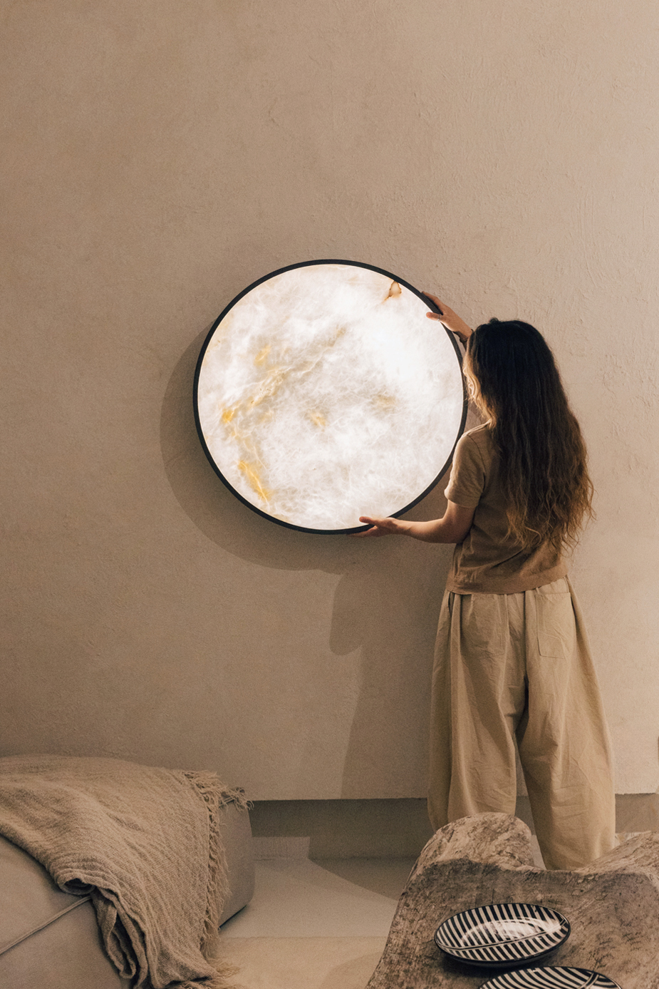 ozeano_studio chica colocando lámpara de pared con forma de luna
